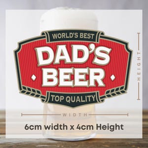 May include: A beer glass with a white foamy head, featuring a red and black label that reads "WORLD'S BEST DAD'S BEER TOP QUALITY". The label is 6cm wide and 4cm high.