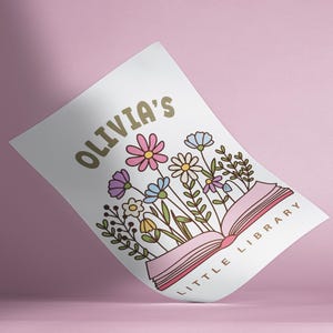 May include: A white print featuring the text "OLIVIA'S LITTLE LIBRARY" in gold, with an open book design. The book is surrounded by colorful flowers in pink, purple, blue, and yellow, with green leaves.