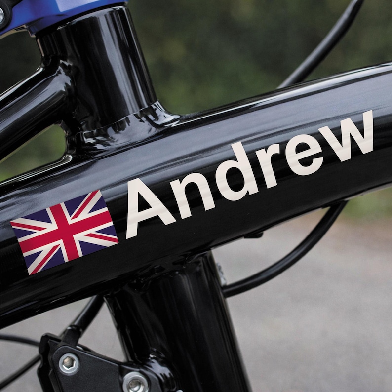 May include: A black bicycle frame with the name "Andrew" in white lettering. A Union Jack flag is on the left side of the name. The bicycle frame is glossy and has a blue accent.