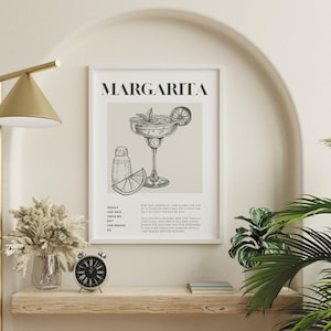 May include: A black and white illustration of a margarita cocktail with a lime wedge and salt on the rim of the glass. The text "MARGARITA" is at the top of the image. The ingredients and instructions for making a margarita are listed below the illustration.