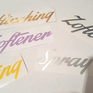 May include: Five different vinyl stickers with cursive lettering. The stickers are in various colors, including gold, purple, yellow, pink, and silver. The words on the stickers are "Hinching", "Softener", "Cleaning", "Lotion", and "Spray".