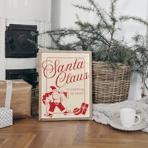 Puede incluir: Una impresi&oacute;n enmarcada con una ilustraci&oacute;n vintage de Santa Claus llevando una bolsa de regalos. El texto dice "Santa Claus is coming to town".