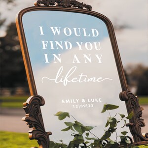 May include: A gold-framed mirror with a white inscription that reads "I would find you in any lifetime." Below the inscription, it says "Emily & Luke 12|09|23".