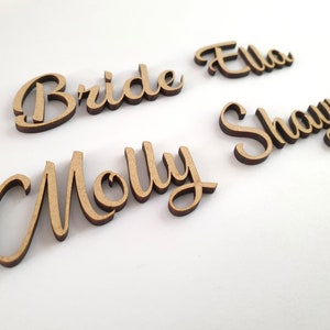 May include: Five wooden signs with the names "Bride", "Molly", "Ella", and "Shayne" written in cursive.