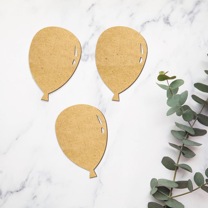 May include: Three brown paper balloon cutouts on a white marble background. The balloons are in the shape of a heart and have a string attached to the bottom.