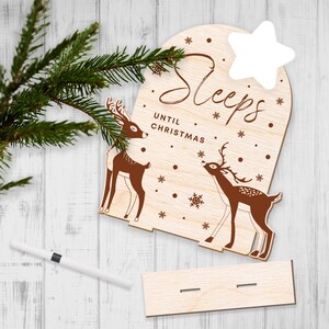May include: Wooden Christmas countdown sign with a white star and two deer. The sign says "Sleeps Until Christmas".
