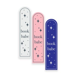 May include: Three bookmark designs with a rounded top and a white border. The bookmarks are in grey, pink, and blue. Each bookmark has a white star pattern and the text "book babe" in white.