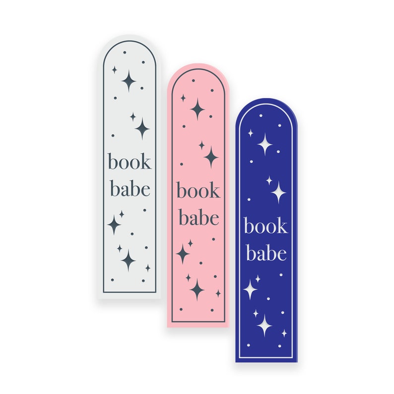 May include: Three bookmark designs with a rounded top and a white border. The bookmarks are in grey, pink, and blue. Each bookmark has a white star pattern and the text "book babe" in white.