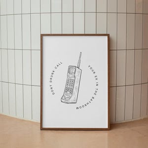 May include: A black and white illustration of a vintage rotary phone with the text "Don't drunk call your ex in the bathroom" around it.