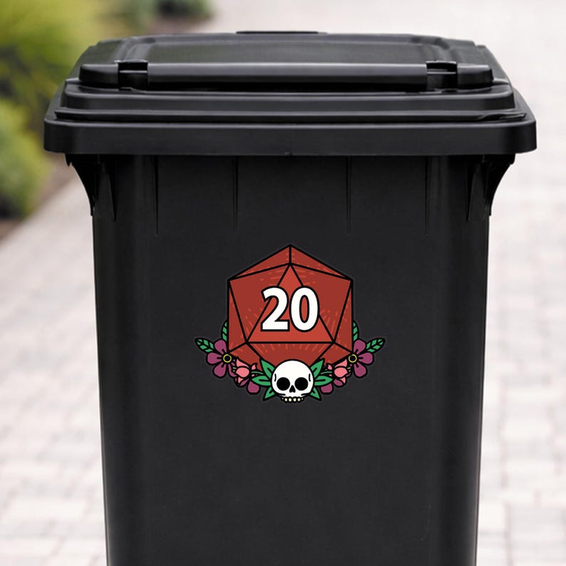 May include: A black trash can with a decorative sticker featuring a red twenty-sided die, a skull, and floral accents. The number 20 is displayed in white. The sticker is centered on the front of the can.