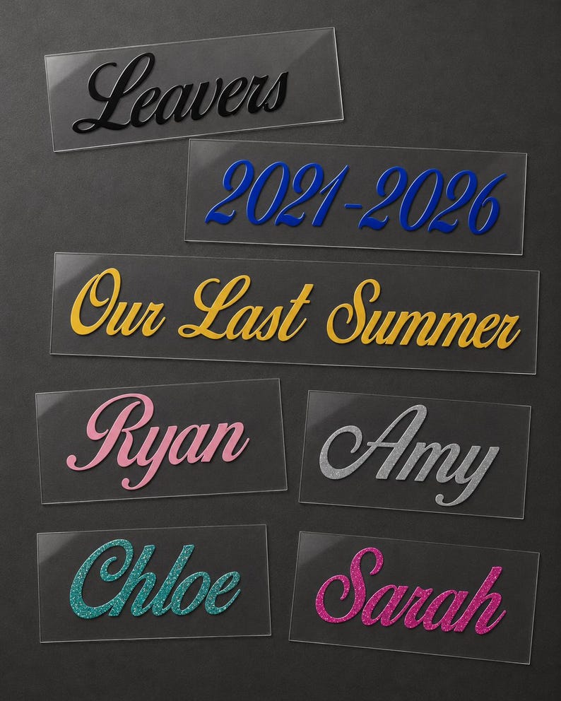 May include: A collection of clear acrylic name tags and labels with various text in different colors. The labels include the words "Leavers", "2021-2026", "Our Last Summer", and names like "Ryan", "Amy", "Chloe", and "Sarah".