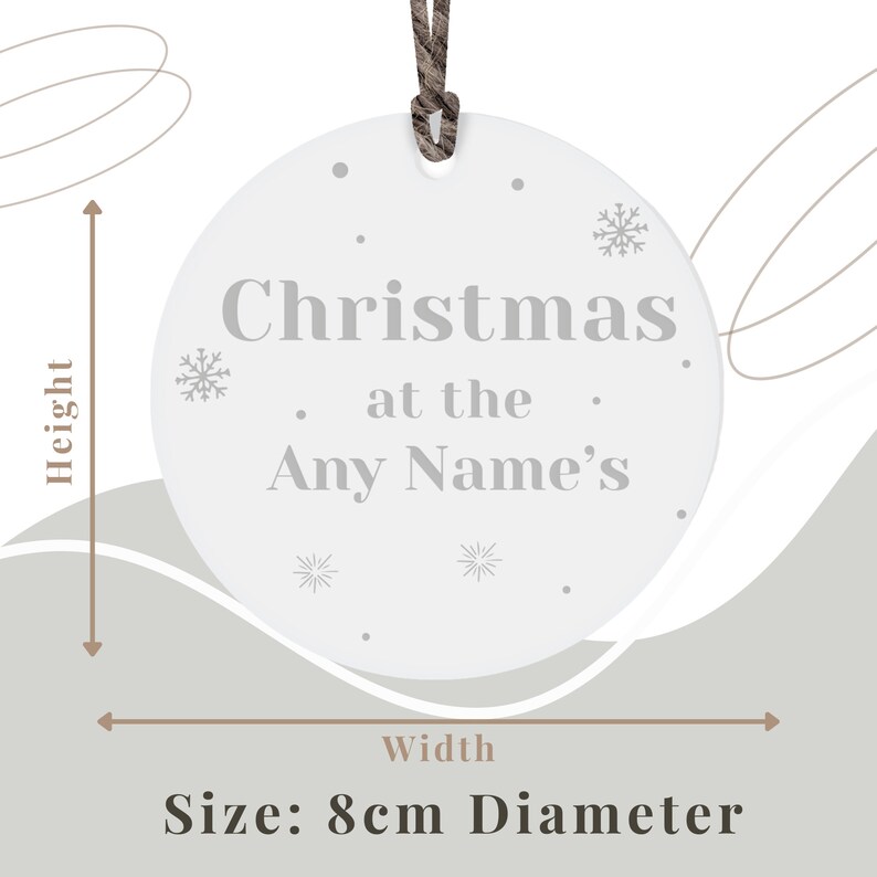 Peut inclure: Ornement de No&euml;l circulaire blanc avec le texte "Christmas at the Any Name's" en gris. L'ornement pr&eacute;sente des motifs de flocons de neige et de points, et une ficelle marron pour l'accrocher. Le diam&egrave;tre est de 8 cm.