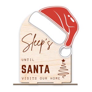 May include: A wooden sign with a red and white Santa hat on top. The sign says "Sleep's Until Santa Visits Our Home".