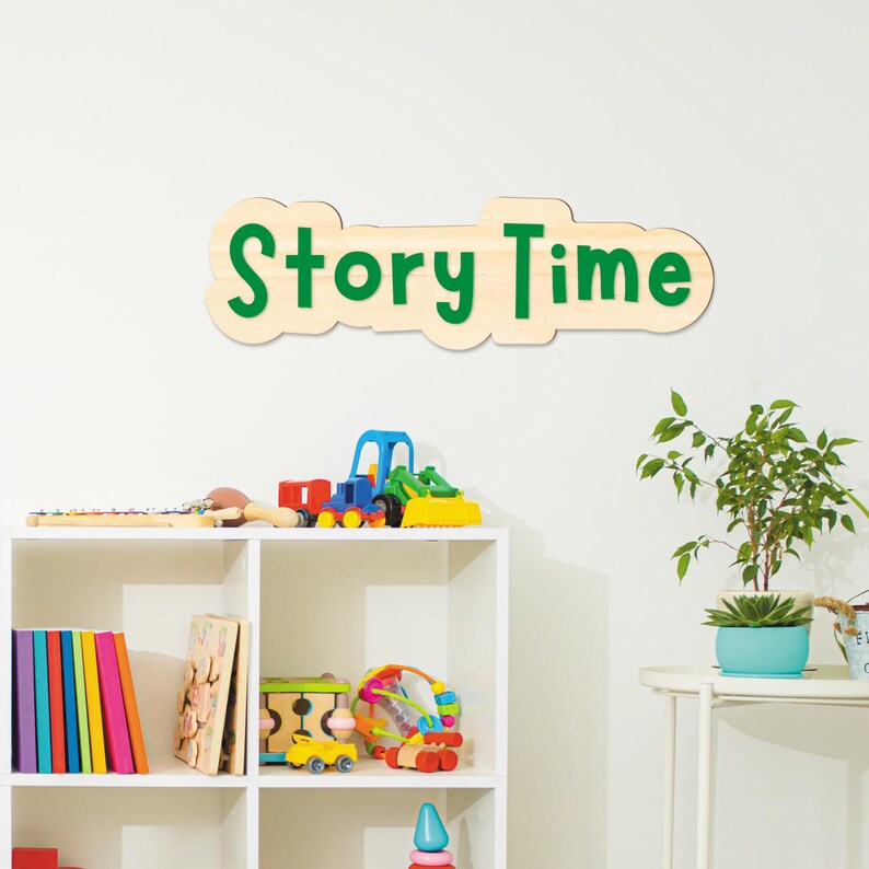 May include: A wooden sign reading "Story Time" in green lettering, mounted on a white wall. Below, a white shelf displays a variety of children's toys, books, and a small potted plant. The scene creates a welcoming atmosphere for reading and play.