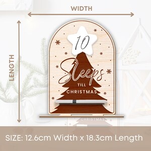 Puede incluir: Un letrero de cuenta atr&aacute;s de Navidad de madera con una estrella blanca y el n&uacute;mero 10 en &eacute;l. El letrero dice "Sleeps Till Christmas" y mide 12,6 cm de ancho y 18,3 cm de largo.