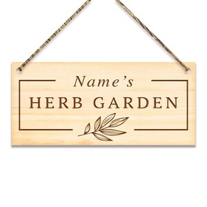 May include: A wooden sign with the text "Name's HERB GARDEN" in brown lettering. The sign has a rope for hanging and a small leaf design.