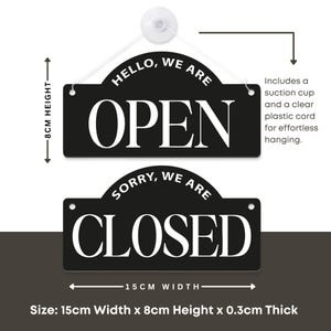May include: Black and white reversible sign with the words "HELLO, WE ARE OPEN" and "SORRY, WE ARE CLOSED". The sign is 15cm wide and 8cm high, and includes a suction cup and clear plastic cord for hanging.