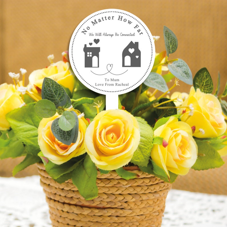 May include: White round sign with the text "No Matter How Far We Will Always Be Connected" with two house silhouettes and hearts. The sign also says "To Mum Love From Rachel".