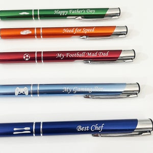 May include: Five different colored pens with silver accents. Each pen has a different design and inscription. The inscriptions are "Happy Father's Day", "Need for Speed", "My Football Mad Dad", "My Gaming Pen", and "Best Chef".