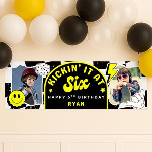 May include: A banner with the text "KICKIN' IT AT Six HAPPY 6TH BIRTHDAY RYAN" in yellow and black. The banner has photos of a child with a skateboard and a smiley face. Black, white, and yellow balloons are in the background.