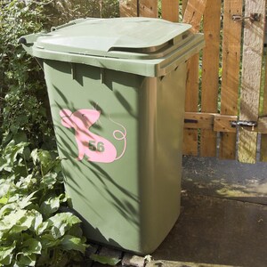 May include: A green recycling bin with a pink mouse sticker with the number 56 on it.