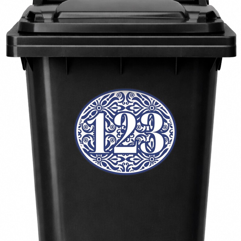 May include: A black trash bin with a white and blue oval sticker. The sticker features the numbers "123" in white, surrounded by a blue and white floral design.
