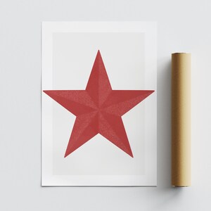 May include: A red star print on white paper. The star is a five-pointed shape with a textured surface. A rolled-up poster is next to the print.