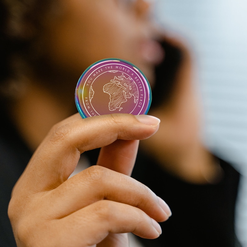 May include: A rainbow iridescent coin with the text "You make the world a better place from the" and a drawing of the world with Africa highlighted.