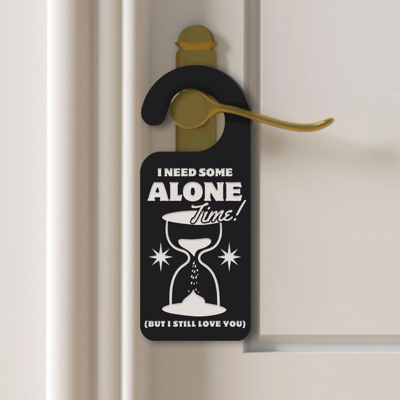 May include: Black door hanger with white text that reads "I need some alone time!" with an hourglass graphic and the text "(But I still love you)".