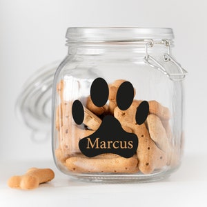 May include: Clear glass jar with a black paw print and the name "Marcus" in orange lettering. The jar is filled with dog biscuits.