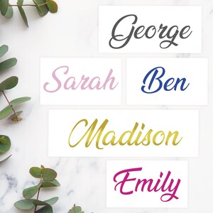 May include: Five white cards with names written in cursive script. The names are George in black, Sarah in pink, Ben in blue, Madison in gold, and Emily in magenta.