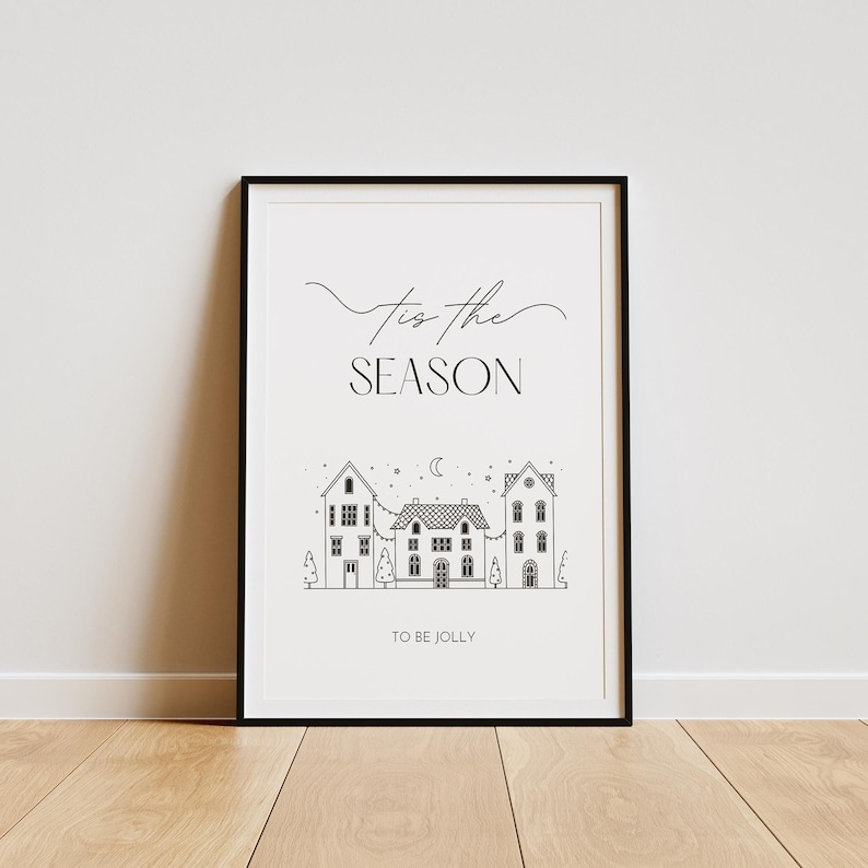 May include: Black and white printable art print with the text "Tis the season to be jolly" and a simple illustration of three houses with a crescent moon and stars in the sky.