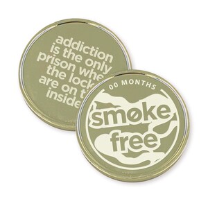 May include: Gold-colored coin with the text "addiction is the only prison where the locks are on the inside" on one side and "00 MONTHS smoke free" on the other side.