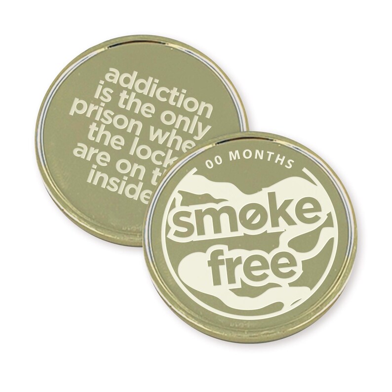 May include: Gold-colored coin with the text "addiction is the only prison where the locks are on the inside" on one side and "00 MONTHS smoke free" on the other side.