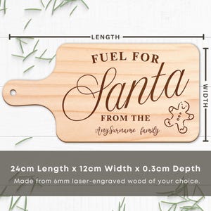 May include: A light-colored wooden cutting board with a handle, engraved with the words "FUEL FOR Santa" and "FROM THE AnySurname family". A gingerbread man is also engraved on the board. The board measures 9.4 inches in length, 4.7 inches in width, and 0.1 inches in depth.