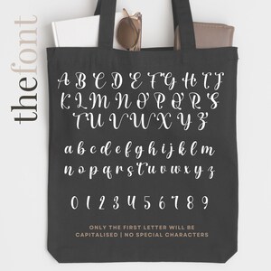 May include: A black tote bag with a white font displaying the alphabet in uppercase and lowercase letters, along with numbers 0-9. The text reads "ONLY THE FIRST LETTER WILL BE CAPITALISED | NO SPECIAL CHARACTERS".