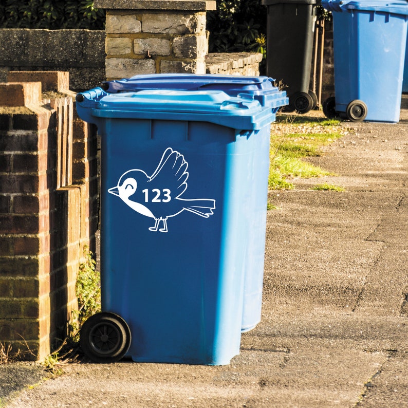 K&ouml;nnte beinhalten: Blaue Recyclingtonne mit einem wei&szlig;en Vogelaufkleber und der Nummer 123.