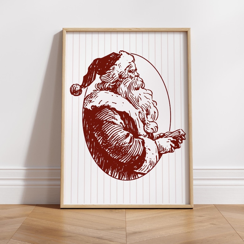 May include: A framed print featuring a vintage illustration of Santa Claus in a burgundy color. The artwork depicts Santa in profile, holding a small object, set against a white background with vertical stripes. The frame is a light wood color.