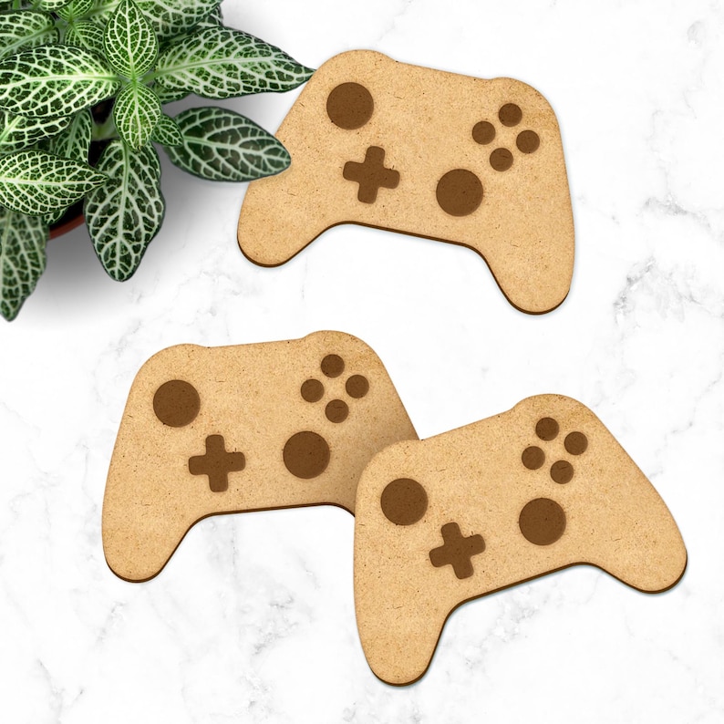 May include: Three wooden game controller coasters. The coasters are brown and have a light brown wood grain. The controllers have a dark brown button design.
