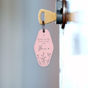 Puede incluir: Un llavero rosa con un dise&ntilde;o floral y el texto "If mum's were like flowers, I would pick You." El llavero est&aacute; unido a una llave de lat&oacute;n en una cerradura de puerta. El llavero tiene un estilo retro de llave de hotel.