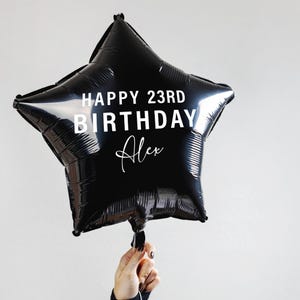 May include: Black star-shaped balloon with the text "Happy 23rd Birthday Alex" in white.