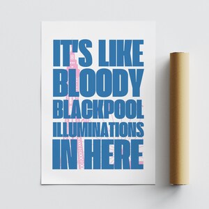 Pu&ograve; includere: Un poster bianco con testo blu che recita "IT'S LIKE BLOODY BLACKPOOL ILLUMINATIONS IN HERE." Un tubo cilindrico marrone &egrave; accanto al poster. Il testo ha un contorno rosa.