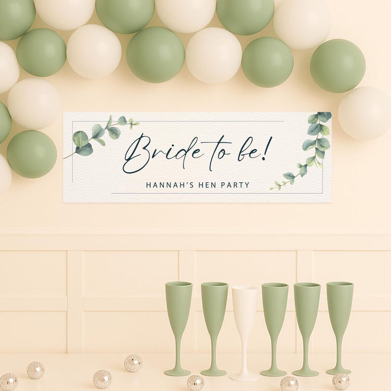 May include: A banner with the text "Bride to be!" and "Hannah's Hen Party" is displayed above six champagne flutes. The flutes are green and white. Balloons in green and white are arranged above the banner.