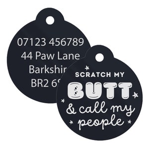 Op de afbeelding: Zwarte ronde hondenpenning met witte tekst. De tekst op de penning luidt "07123 456789, 44 Paw Lane, Barkshir, BR2 6" aan de ene kant en "SCRATCH MY BUTT & call my people" aan de andere kant.