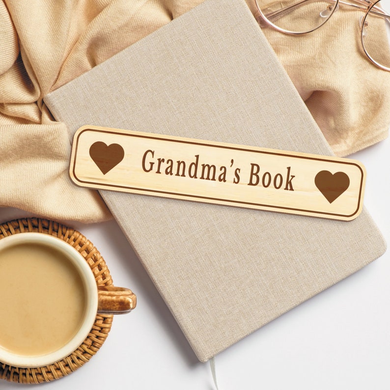 Op de afbeelding: Een houten bladwijzer met een hart aan elk uiteinde en de tekst "Grandma's Book" in bruine letters.