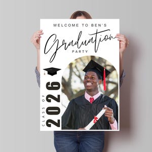 May include: A white graduation party poster with the text "Welcome to Ben's Graduation Party" in black script. The poster features a photo of a graduate in a cap and gown, and the text "Class of 2026".