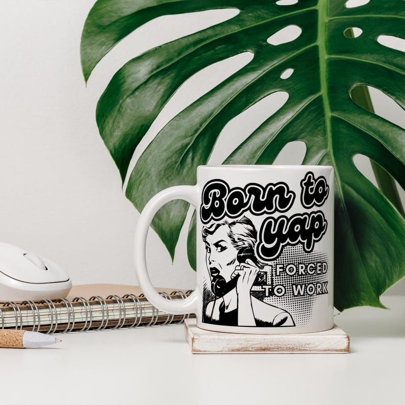 May include: White ceramic mug with a black and white illustration of a woman on the phone. The text "Born to yap forced to work" is printed on the mug.