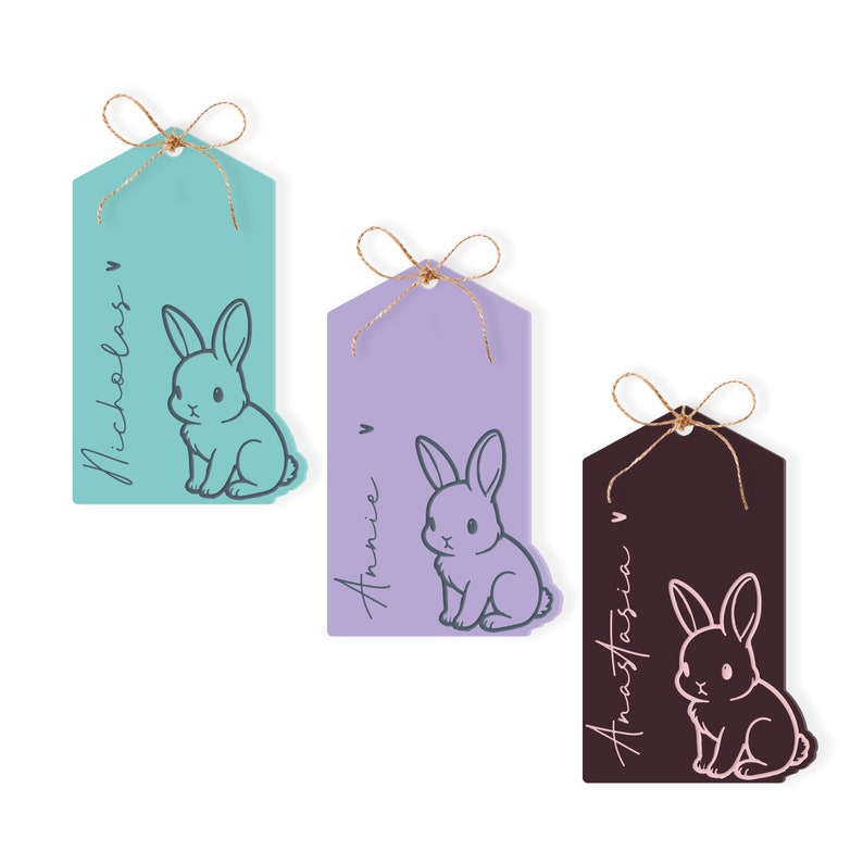 May include: Three gift tags with bunny illustrations. The tags are teal, purple, and brown. The names "Nicholas", "Annie", and "Anastasia" are written on the tags.