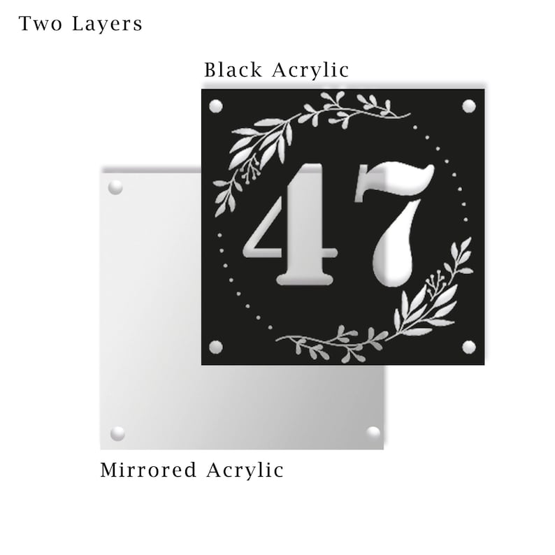 May include: Two-layer house number sign with the number 47 in white on a black background. The number is surrounded by a white floral wreath. The sign is made of acrylic.