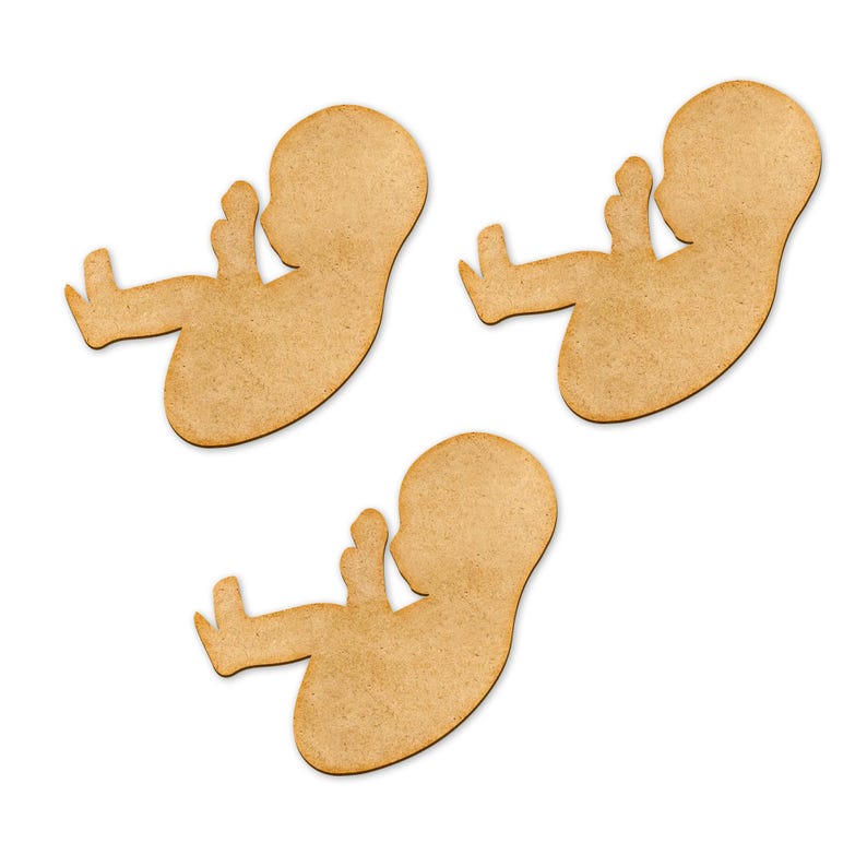 May include: Three wooden cutouts in the shape of a fetus, each with a light brown color and a smooth texture. The cutouts are arranged on a white background. The fetus cutouts are a craft supply.